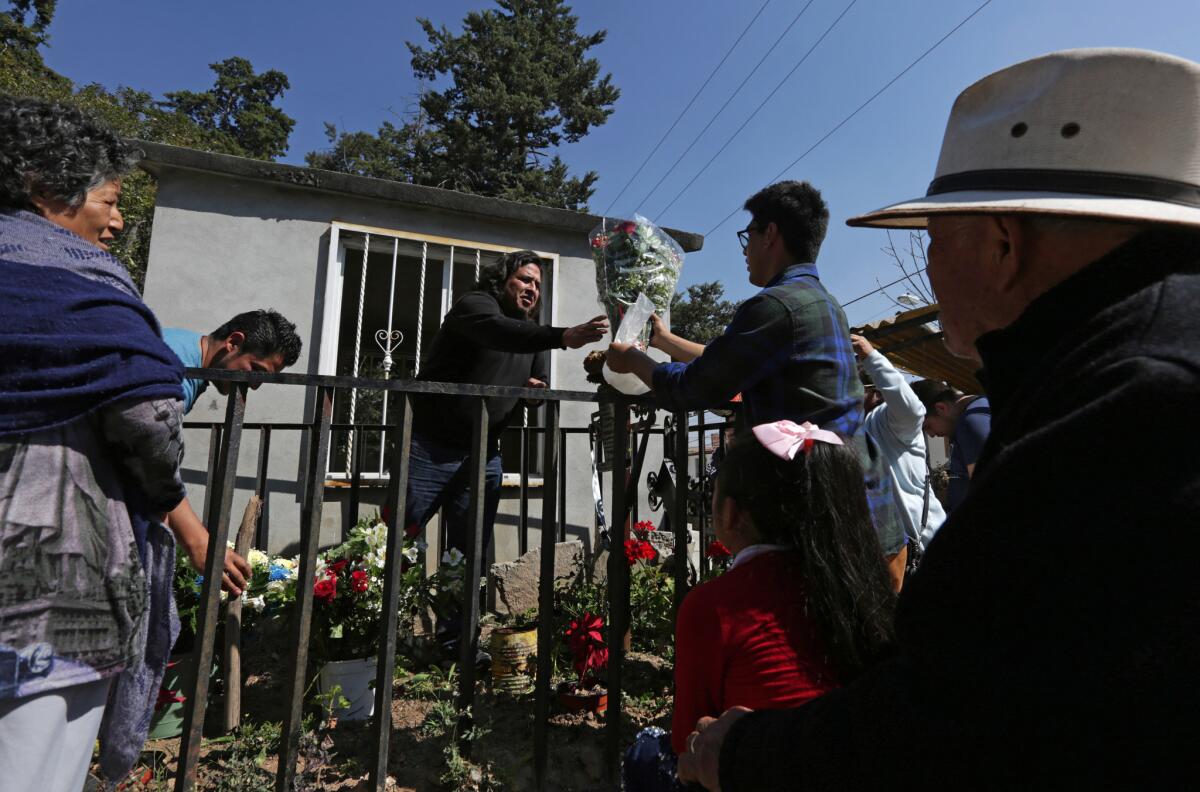 Edgar hands flowers to his brother, Hugo, to place on their father’s grave. (Katie Falkenberg / Los Angeles Times)