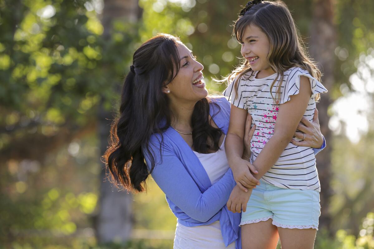 A woman and her daughter laugh and embrace outside