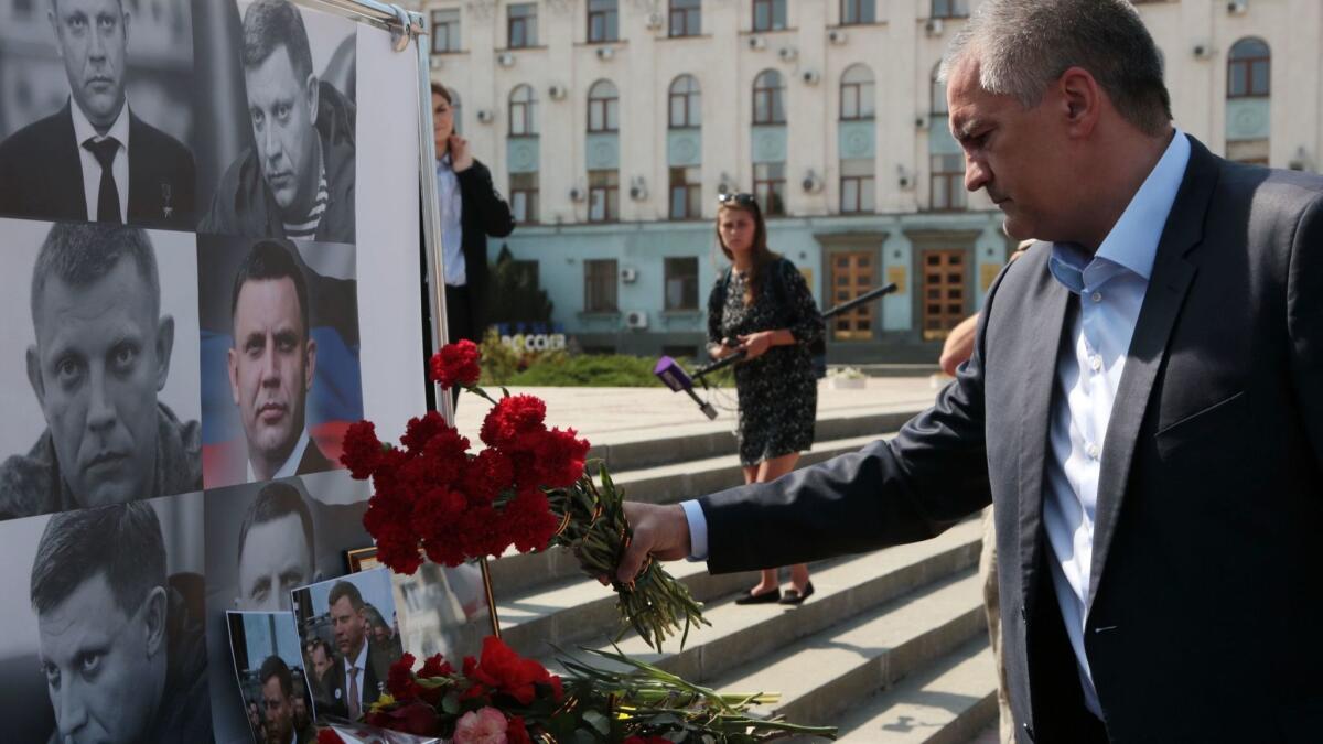 Crimean leader Sergei Aksyonov lays flowers at a makeshift memorial for Alexander Zakharchenko in Simferopol on Sept. 1, 2018.