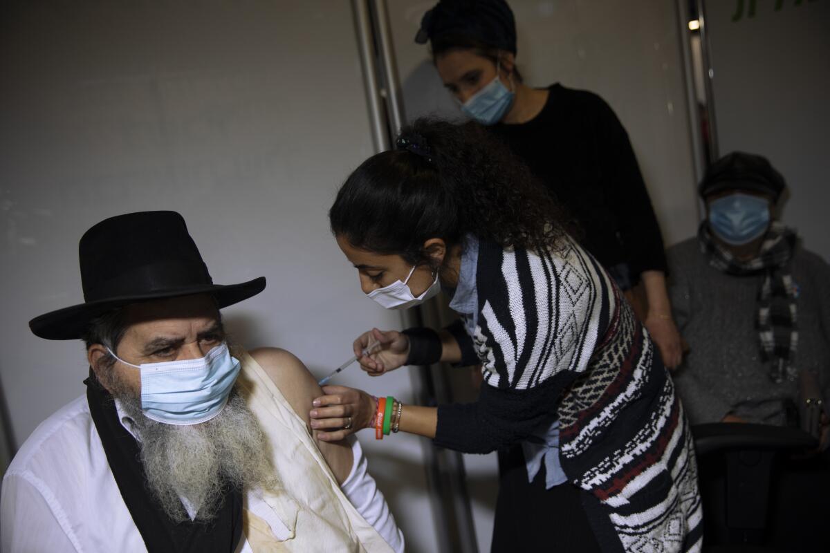 A man receives a coronavirus shot from medical staff at a COVID-19 vaccination center in Jerusalem on Monday.