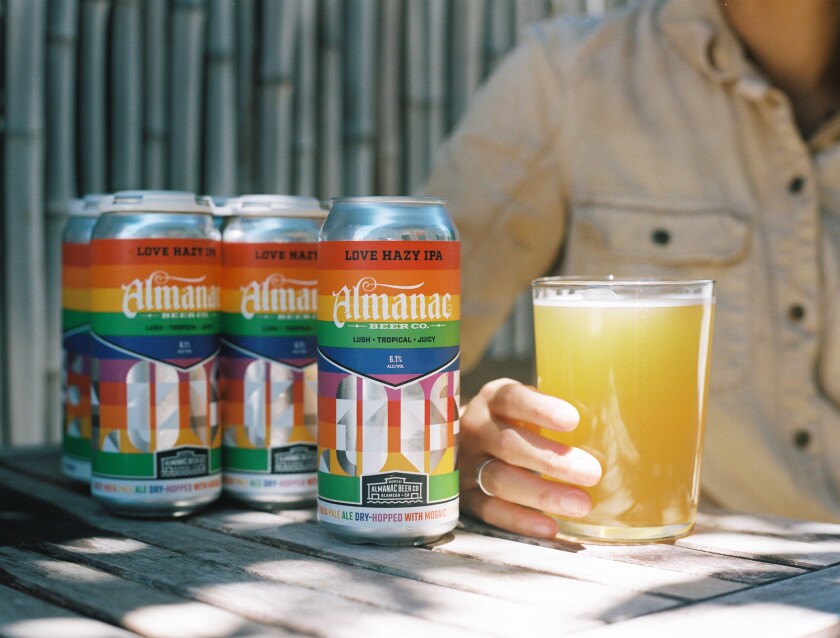 A glass of Almanac Beer Co.'s product is to the right of three cans of beer.
