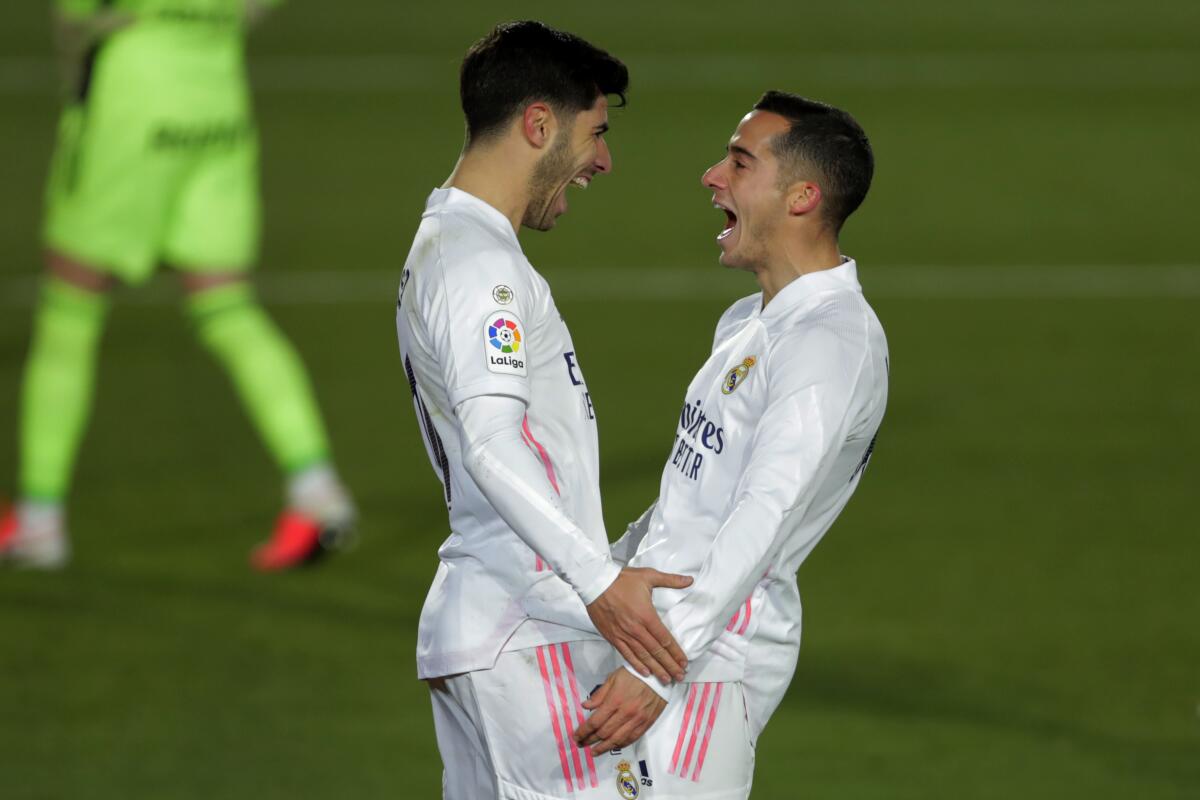 Real Madrid's Marco Asensio, left, celebrates with teammate Lucas Vazquez after scoring his side's second goal during the Spanish La Liga soccer match between Real Madrid and Celta Vigo at the Alfredo Di Stefano stadium in Madrid, Spain, Saturday, Jan. 2, 2021. (AP Photo/Manu Fernandez)