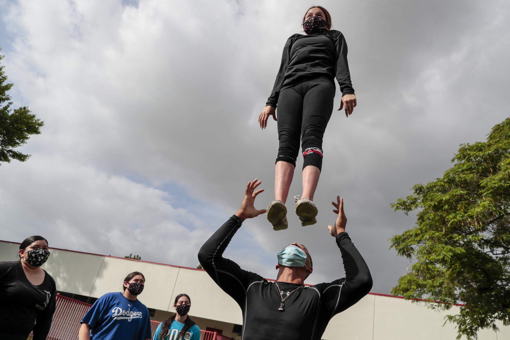 Johnny Sen practices catching fellow senior Breanna Razo during cheer practice.