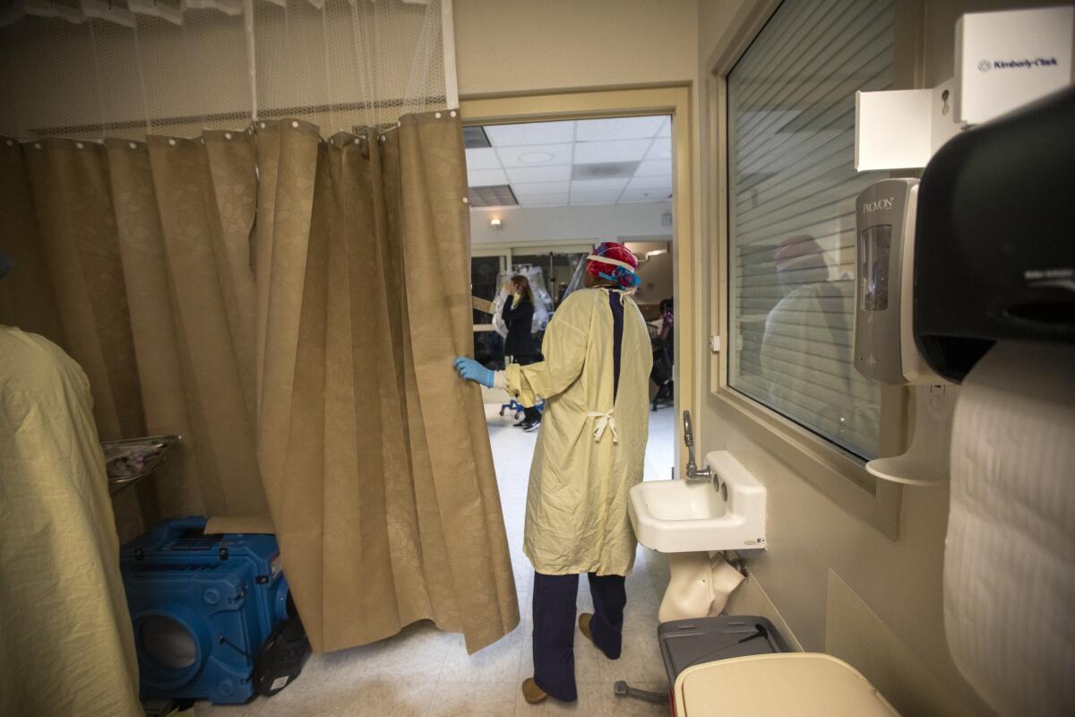 A doctor peers out from behind an emergency room curtain. 