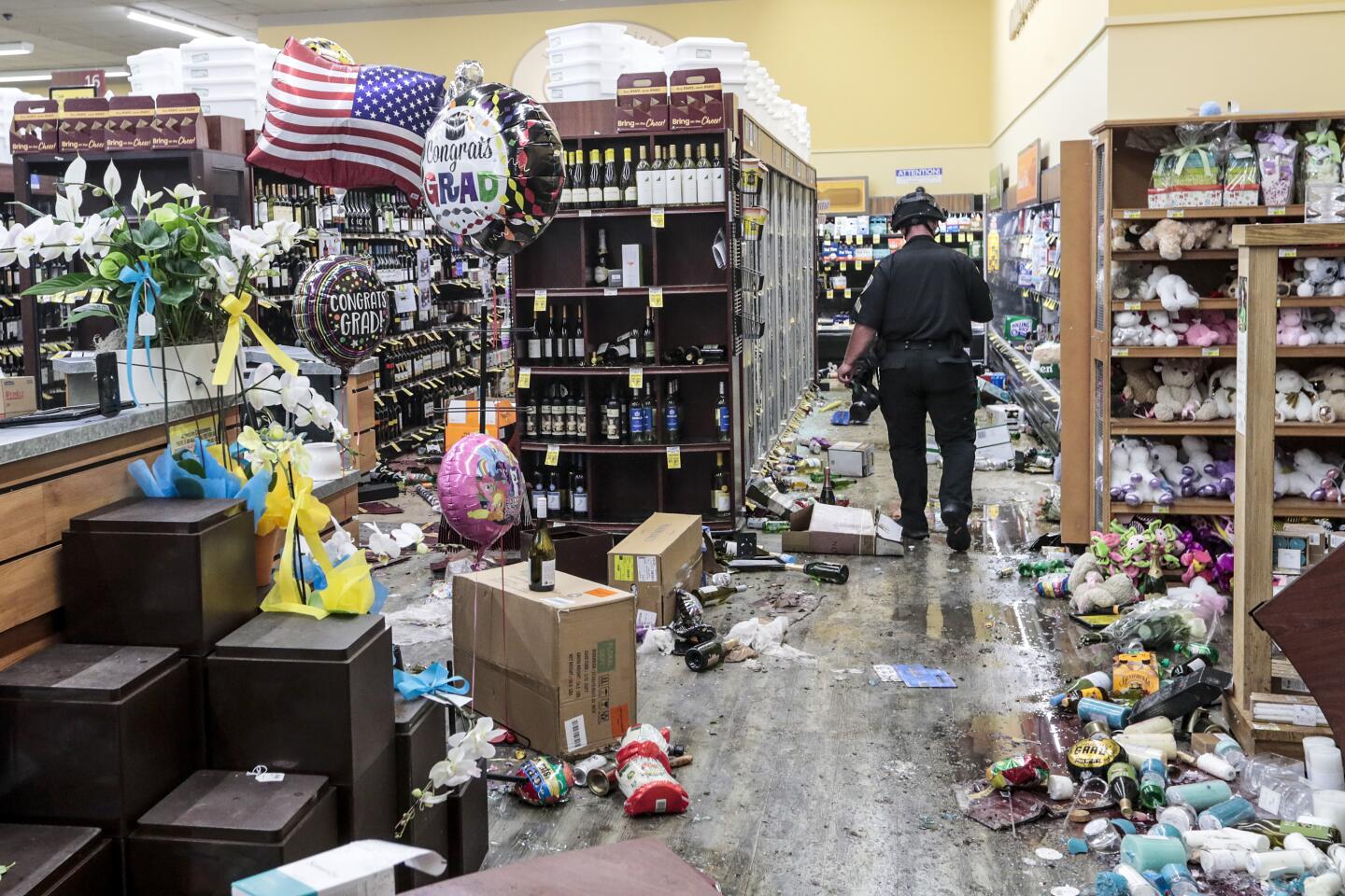 A police officer inspects the damage to a supermarket.