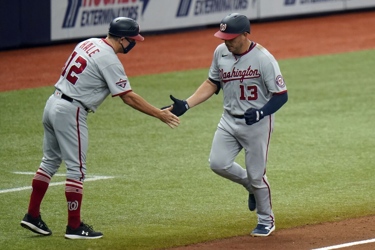 Washington Nationals' Asdrubal Cabrera (13) shakes hands with third base coach Chip Hale (12) after Cabrera hit a two-run home run off Tampa Bay Rays pitcher Oliver Drake during the sixth inning of a baseball game Wednesday, Sept. 16, 2020, in St. Petersburg, Fla. (AP Photo/Chris O'Meara)
