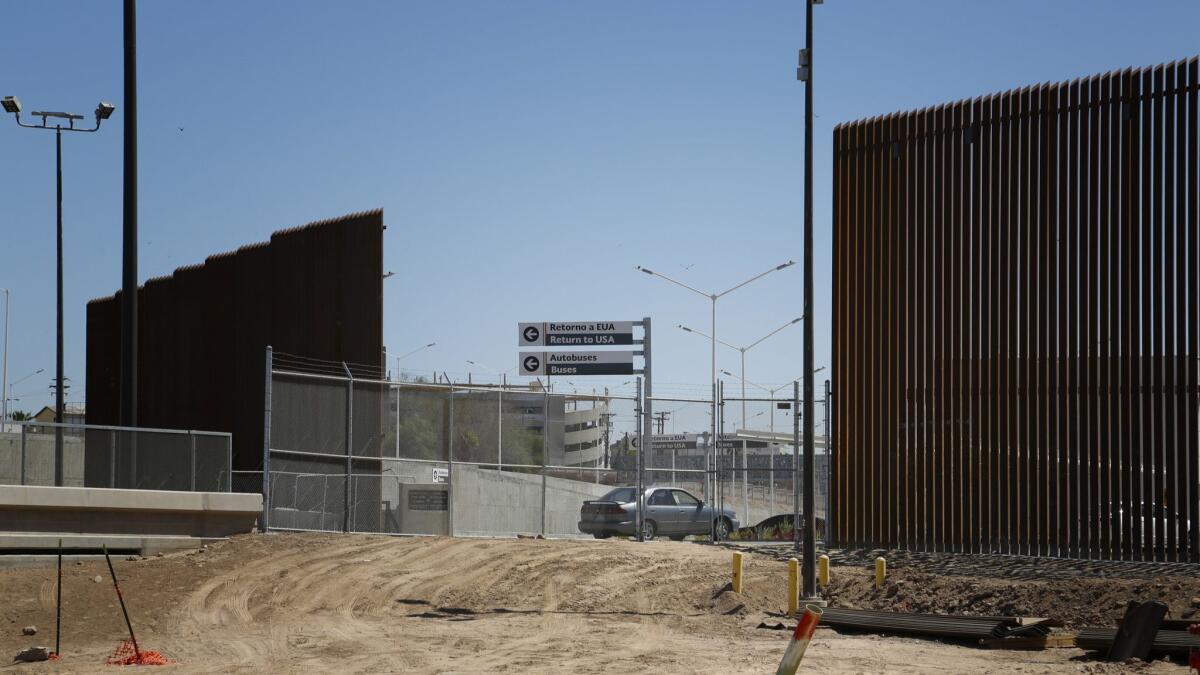 Passing between sections of a recently completed, replacement border barrier, cars cross into Mexico through travel lanes at Calexico's new port of entry.