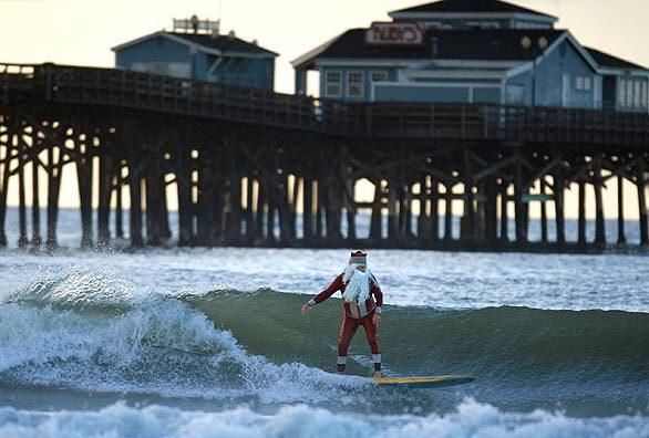 THAT'S NO SLIEGH: Michael Pless, 58, aka the Surfing Santa, rides waves at the Seal Beach Pier as he's done every December for years.
