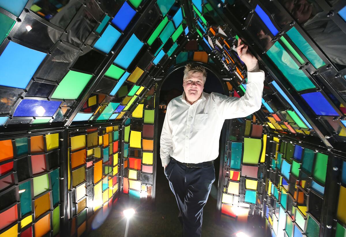 Artist Tom Fruin stands inside his "Camouflage House," a public art piece in front of Laguna Beach City Hall. The work — an A-frame metal house fitted with a mosaic of stained glass — was revealed Monday evening and will be on display until April.