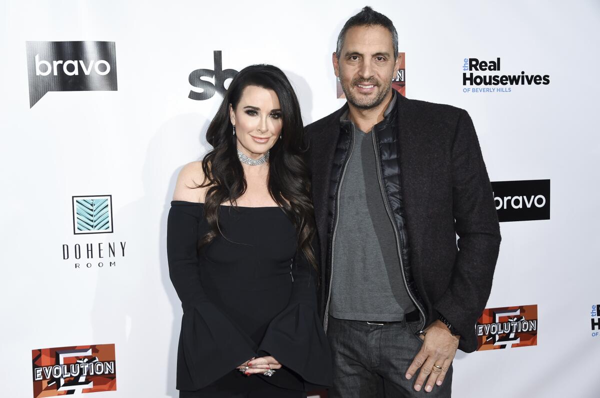 Kyle Richards stands in a black dress with Mauricio Umansky, who is in a black jacket and pants with a gray shirt 
