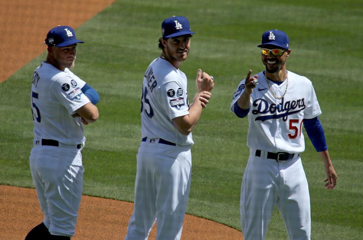 From left, the Dodgers' Matt Beaty, Cody Bellinger and Mookie Betts celebrate during a pregame ring ceremony Friday.