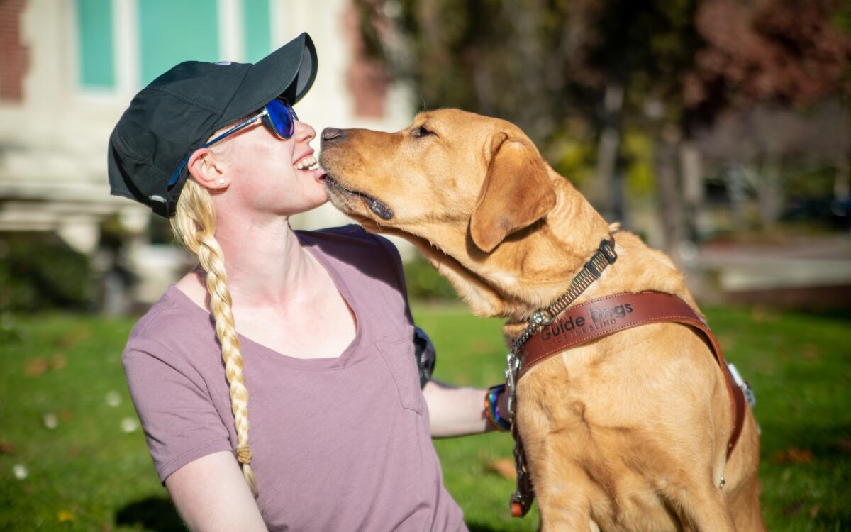 Paralympic runner Kym Crosby laughs as her guide dog Tron licks her face.