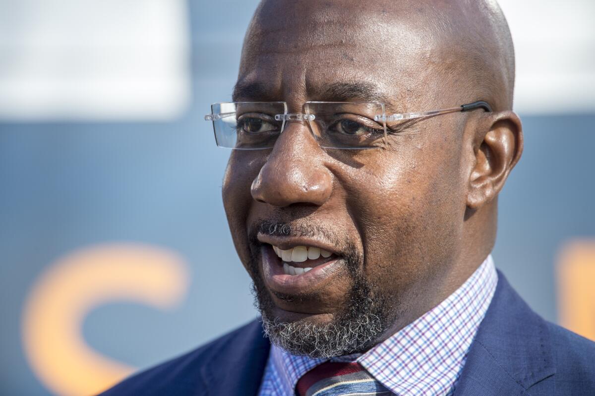 Georgia Democratic senate candidate Raphael Warnock talks to reporters following a campaign rally in Augusta, Ga., Monday, Jan. 4, 2021. Democrats Jon Ossoff and Warnock are challenging incumbent Republican Senators David Perdue and Kelly Loeffler in a runoff election on Jan. 5. (Michael Holahan/The Augusta Chronicle via AP)