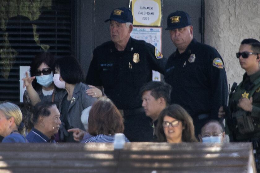 Laguna Woods, CA - May 15: Law enforcement officers stand guard as parishioner gather and comfort each other after a person opened fire during a church service attended by a Taiwanese congregation, killing one person and critically injuring four others at Geneva Presbyterian Church in Laguna Woods Sunday, May 15, 2022. Authorities are interviewing more than 30 people who were inside the church at the time. The victims were described as mostly Asian and mostly of Taiwanese descent, authorities said. A law enforcement source said officials believe the suspect was a 68-year-old Asian man who is originally from Las Vegas. The source said after the suspect opened fire he was "subdued" by parishioners. No other details were available. (Allen J. Schaben / Los Angeles Times)