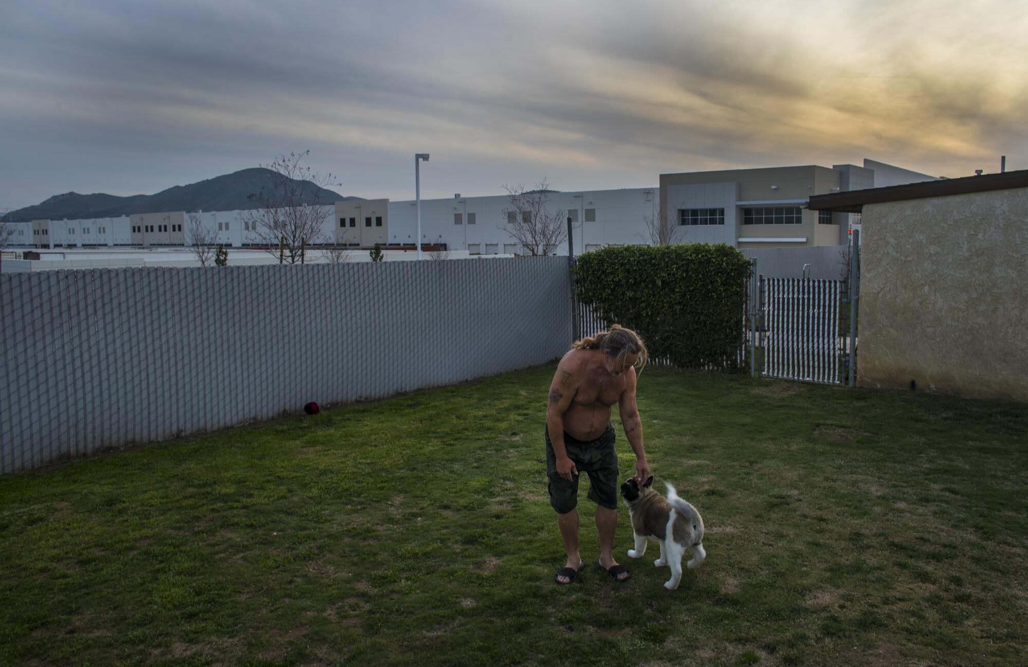 Jerry Denney, in the frontyard of his 35-year Fontana home, has a view of a warehouse and hears trucks day and night.