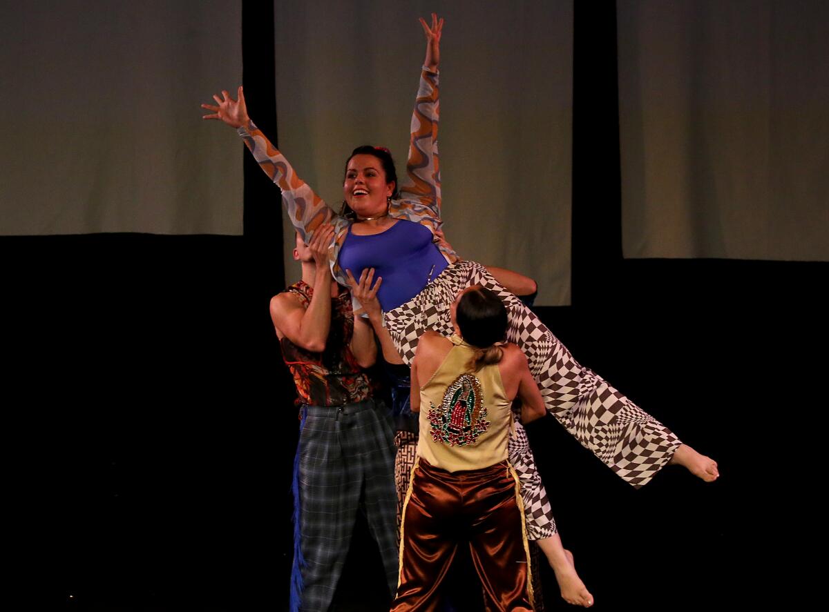 Two male dancers lift a female dancer