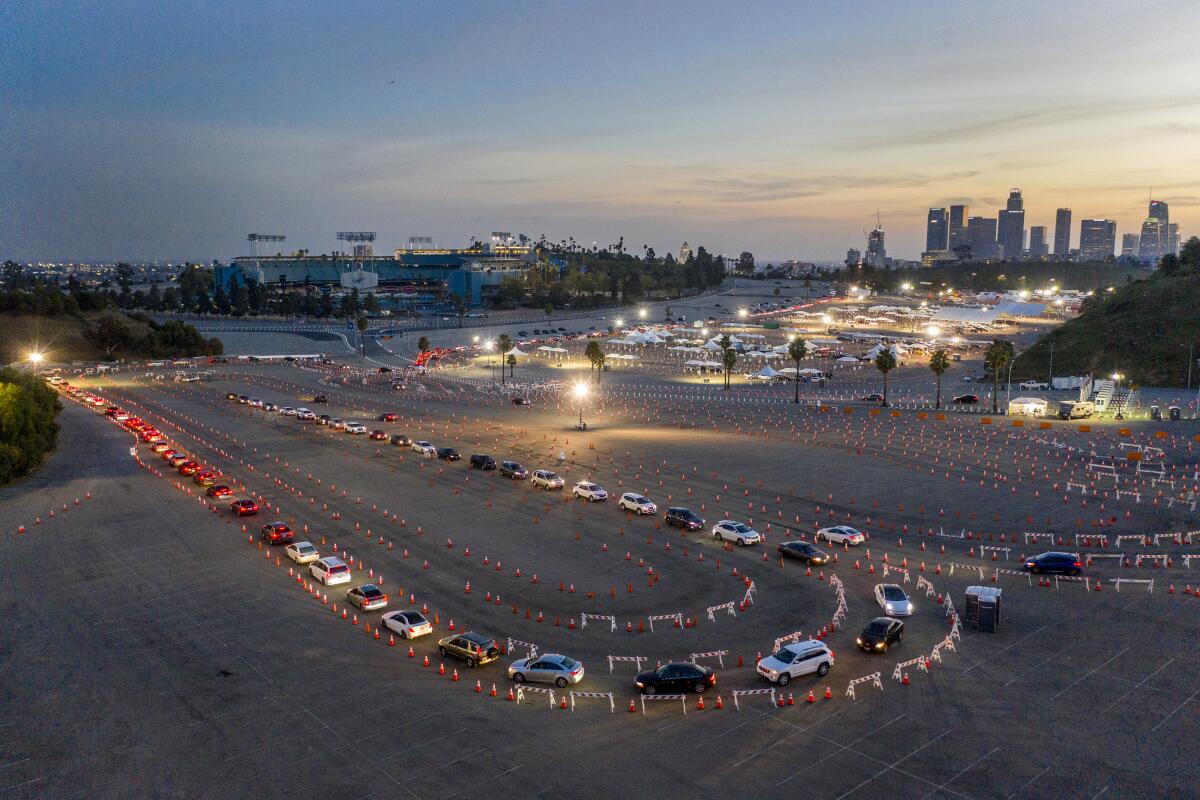 A long line of cars snaking through orange cones in the Dodger Stadium parking lot at dusk.