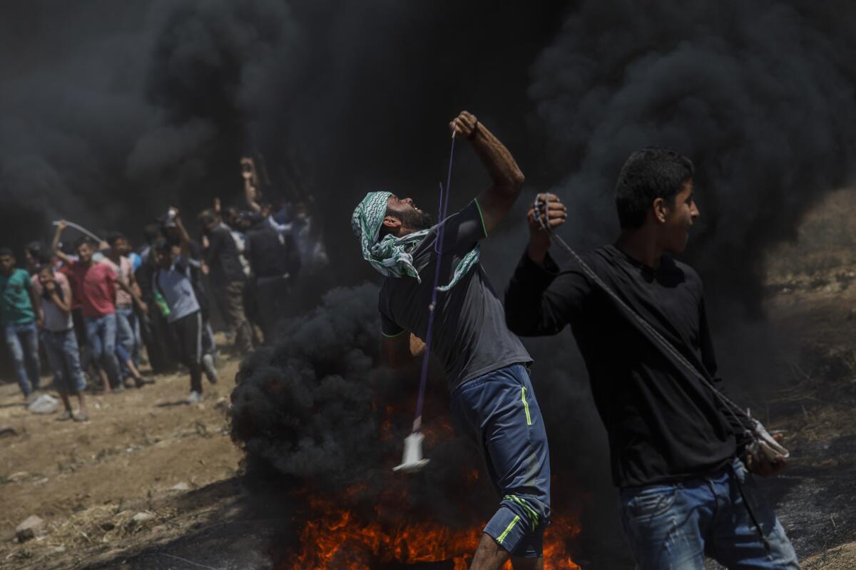 Protesters fling projectiles at the border fence separating Israel and Gaza in a camp east of Gaza City on Monday.