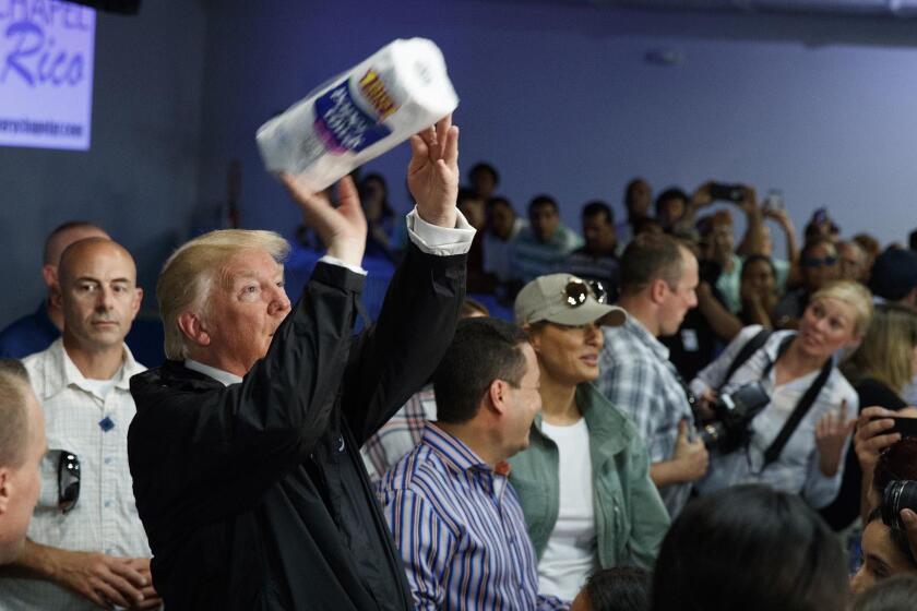 President Donald Trump tosses paper towels into a crowd as he hands out supplies at Calvary Chapel, Tuesday, Oct. 3, 2017, in Guaynabo, Puerto Rico. Trump is in Puerto Rico to survey hurricane damage. (AP Photo/Evan Vucci)