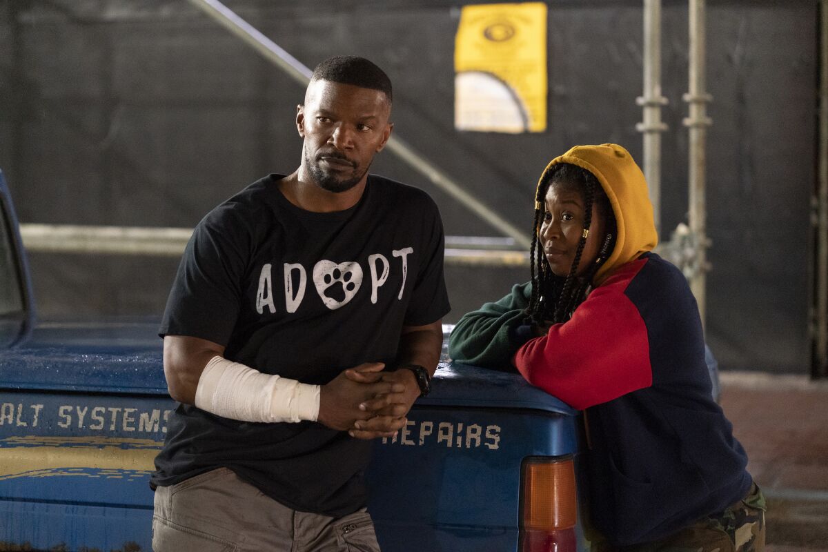 This image released by Netflix shows Jamie Foxx, left, and Dominique Fishback in a scene from "Project Power." (Skip Bolen/Netflix via AP)