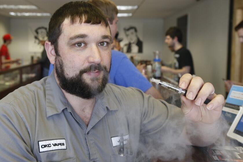 John Durst demonstrates the use of an electronic cigarette at his shop in Oklahoma City. Marlboro maker Altria Group Inc. said Thursday it is rolling out an electronic cigarette.