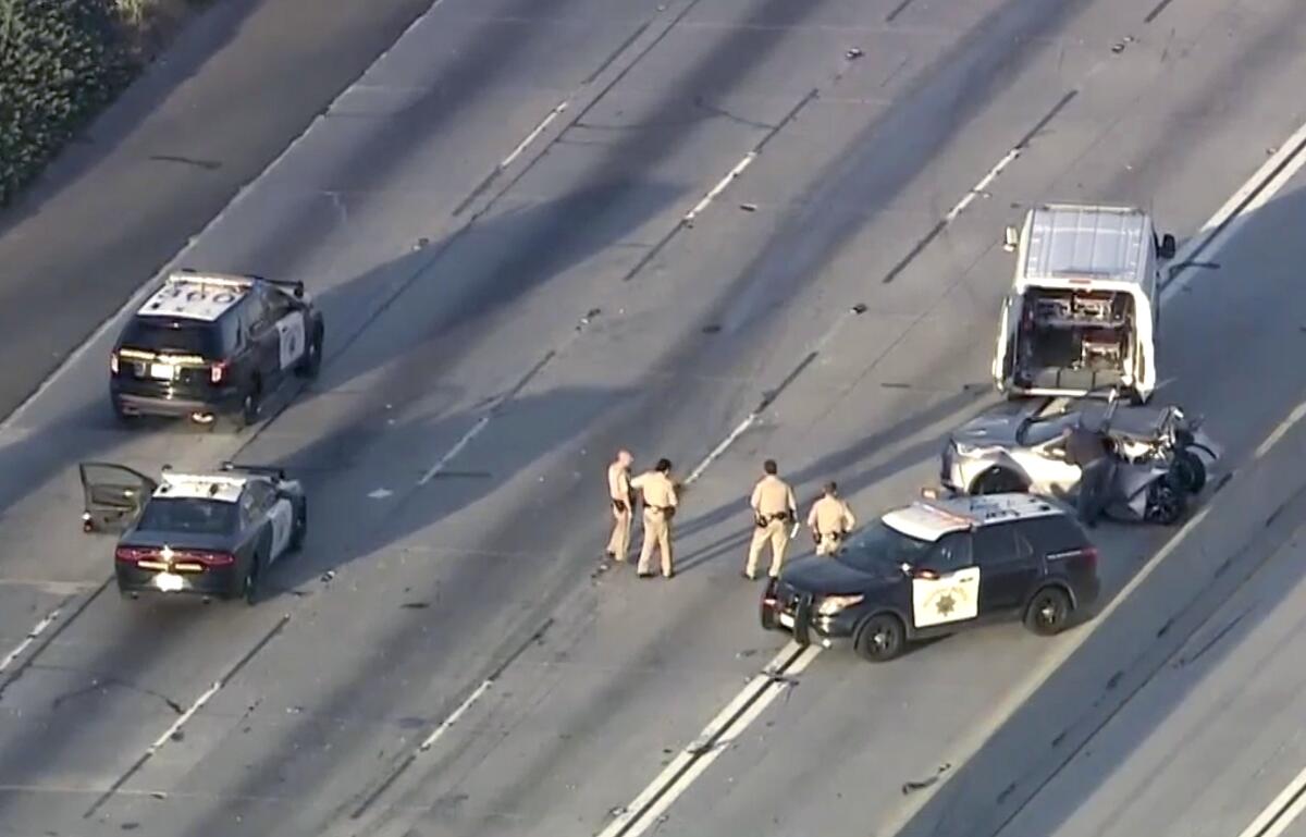 A wrecked car, police officers and emergency vehicles on an empty freeway 