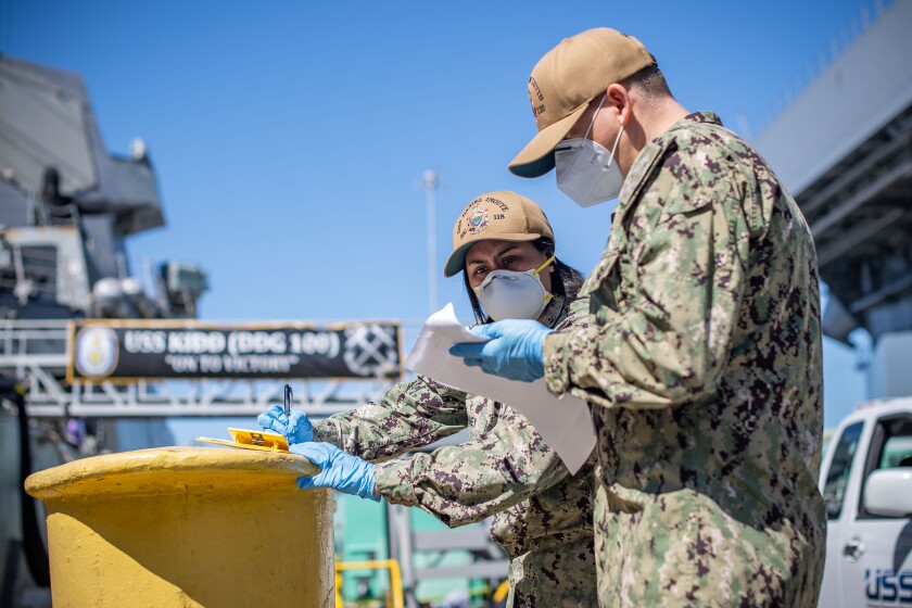 SAN DIEGO (May 18, 2020) – Chief Cryptologic Technician Marisol Swenney and Senior Chief Fire Controlman Michael Miller confirm muster sheets during crew swap, for the guided-missile destroyer USS Kidd. The Navy re-tested the crew for COVID-19 and transferred nearly 90 sailors from quarantine to the ship Monday.