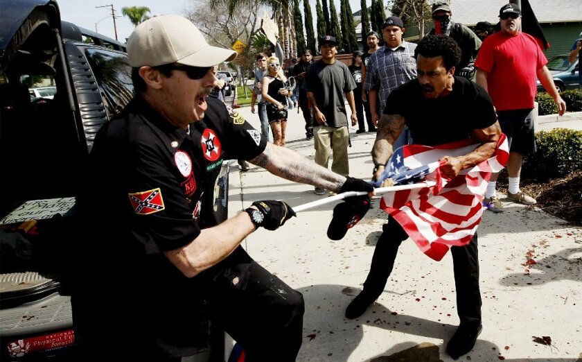 A Ku Klux Klansman, left, fights a counter-protester for an American flag after members of the KKK tried to hold a rally at Pearson Park in Anaheim in February. Seven counter-protesters have now been charged with attacking Klan members at the rally.