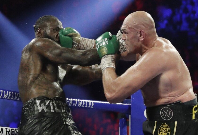 FILE - In this Feb. 22, 2020, file photo, Tyson Fury, right, of England, lands a right to Deontay Wilder during a WBC heavyweight championship boxing match in Las Vegas. A person with knowledge of the situation says Fury has tested positive for COVID-19, and his third bout with Wilder will be postponed, likely until the fall. The person spoke to The Associated Press on condition of anonymity Thursday, July 8, because the promoters of the lucrative heavyweight trilogy are still finalizing the new date. (AP Photo/Isaac Brekken, File)