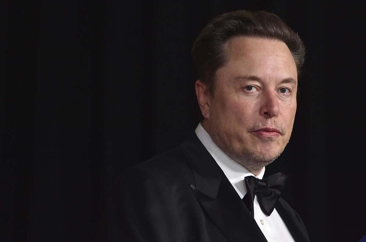 Elon Musk in a black tuxedo against a dark backdrop.