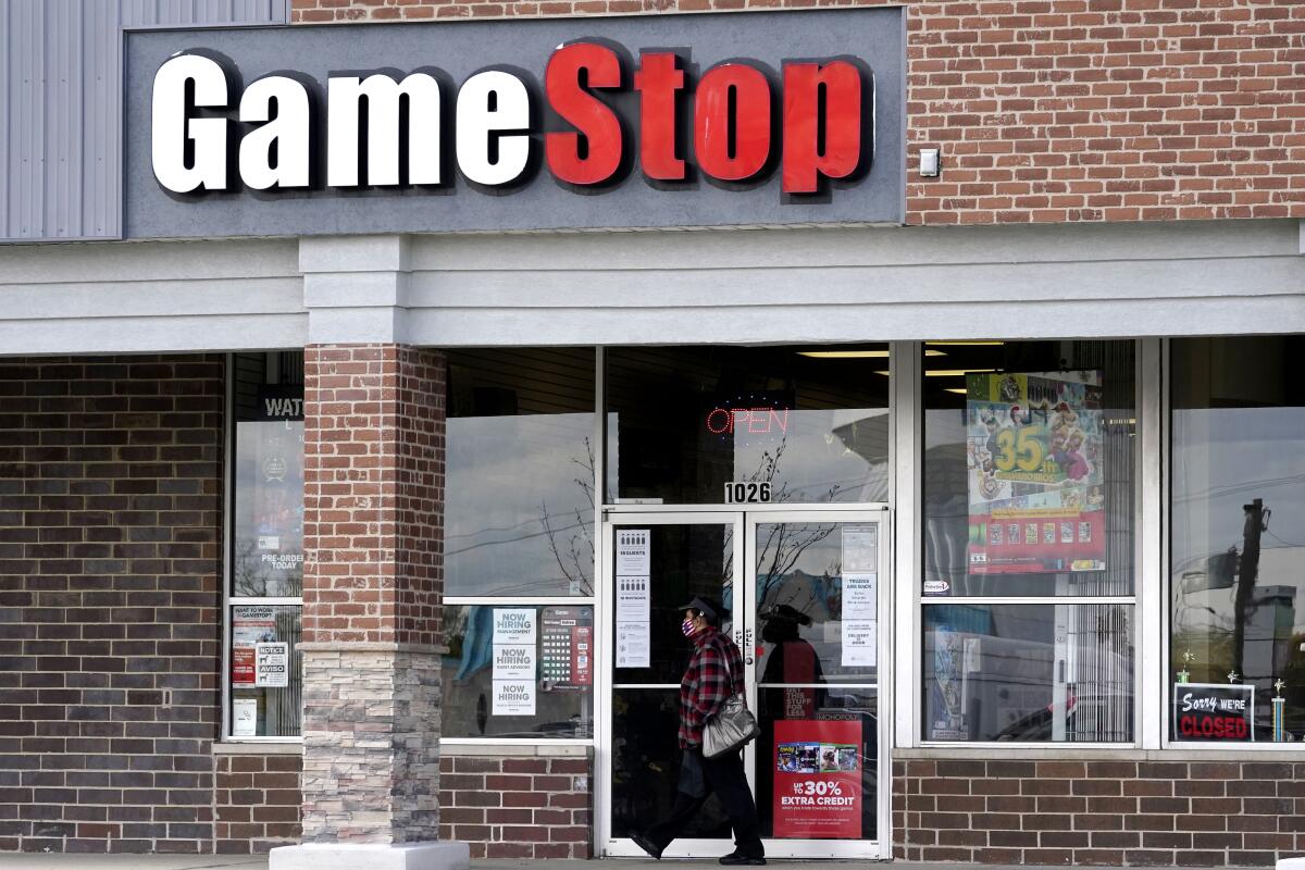 A woman wears a face mask as she walks past a GameStop store in Des Plaines, Ill., in October 2020.