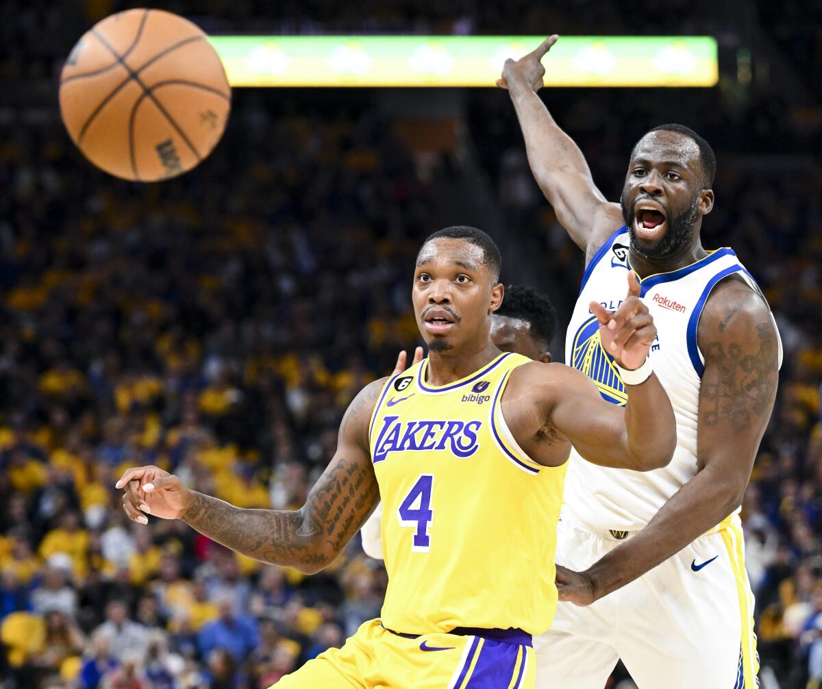 Forward Draymond Green points for Warriors ball as Lakers guard Lonnie Walker IV, left, watches it goes out of bounds.