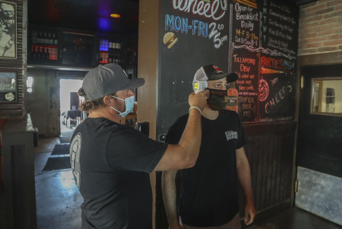 Owner Ben Clevenger (left) takes the temperature of /lead bartender Curtis Schussler at Eastbound Bar and Grill in Lakeside. 