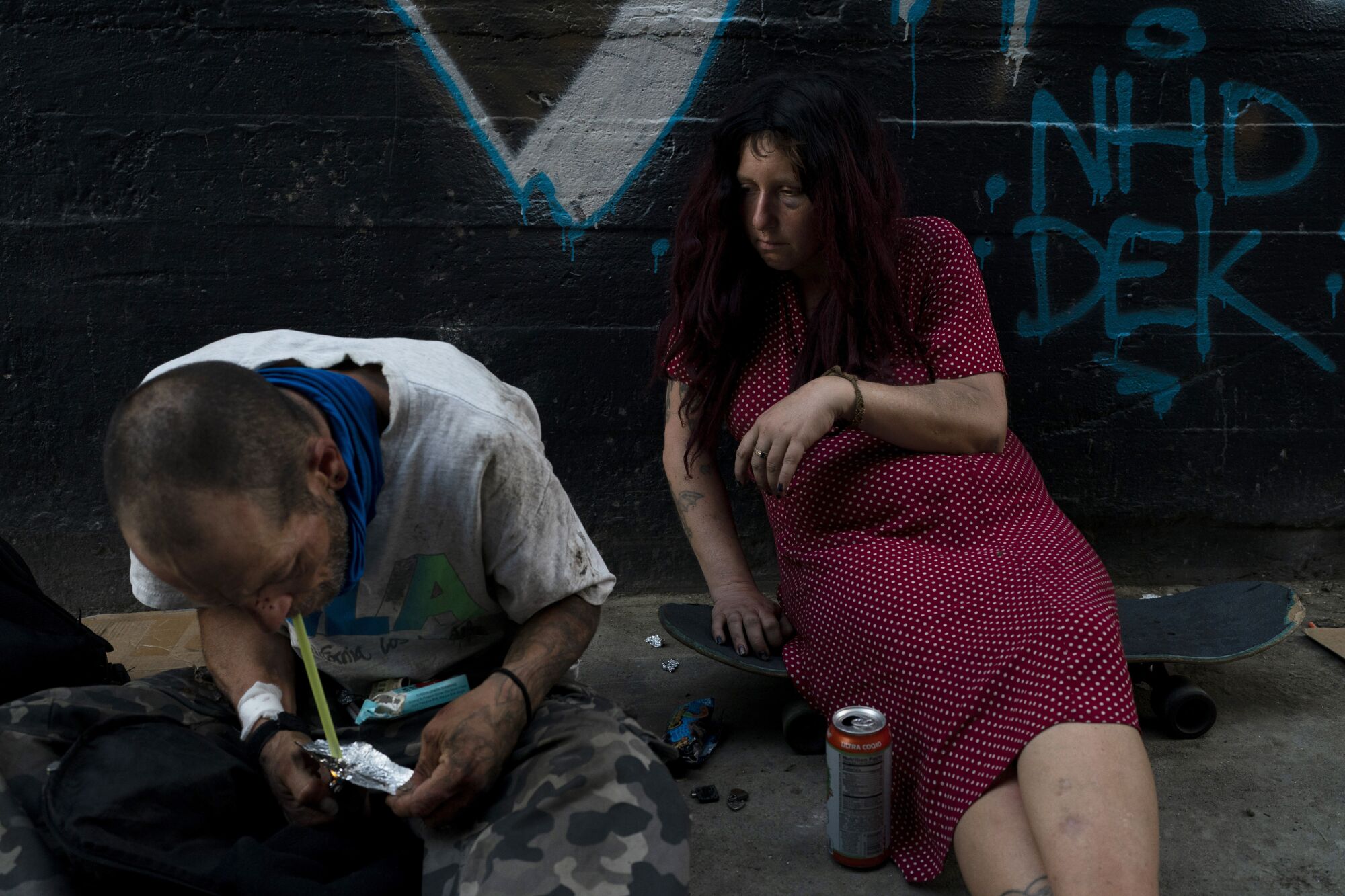 Jenn Bennett, who is high on fentanyl, sits on her skateboard as her friend Jesse Williams smokes the drug.