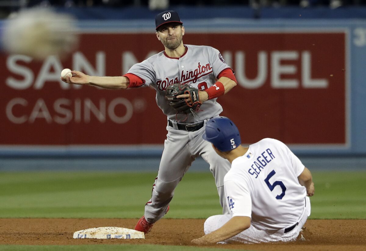 Washington Nationals second baseman Brian Dozier, top, completes a double play over Dodgers' Corey Seager after a ground ball from Chris Taylor during the fourth inning on Thursday at Dodger Stadium.