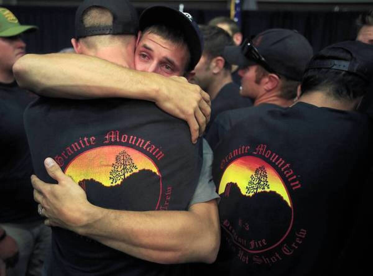 Fellow firefighters embrace at a public memorial service for the 19 crew members who were killed battling a blaze in Arizona.