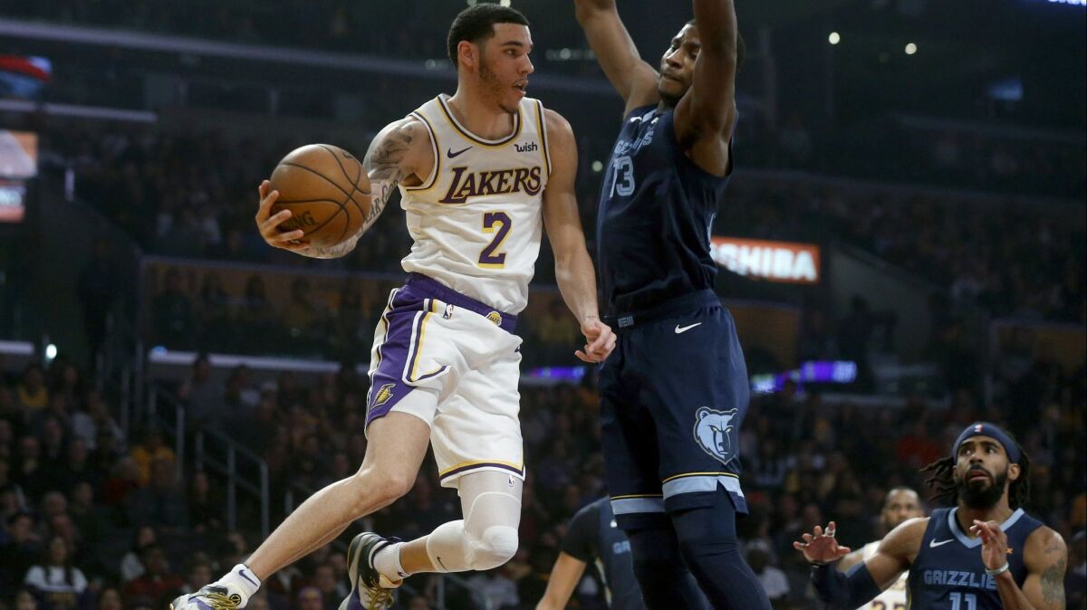 Lakers guard Lonzo Ball attempts a pass while being guarded by Memphis Grizzlies forward Jaren Jackson Jr. (13) in the first half at the Staples Center on Sunday.