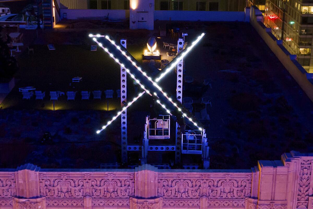 ARCHIVO - Trabajadores instalan luces en un letrero de "X" encima de la sede de la compañía.