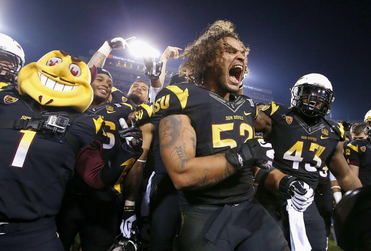 Arizona State's Carl Bradford, middle, celebrates with teammate Davon Coleman (43) and mascot Sparky after defeating Arizona, 58-21, on Nov. 30. Some Arizona State players are having fluids drawn and their on-field hits measured as part of study to identify bio-markers that indicate a player has a concussion.