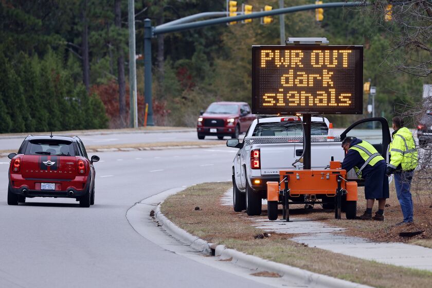 Workers set up an automated display warning drivers on NC211 of the power outage in the area and how to approach the upcoming intersections in Southern Pines, N.C., Monday, Dec. 5, 2022. (AP Photo/Karl B DeBlaker)