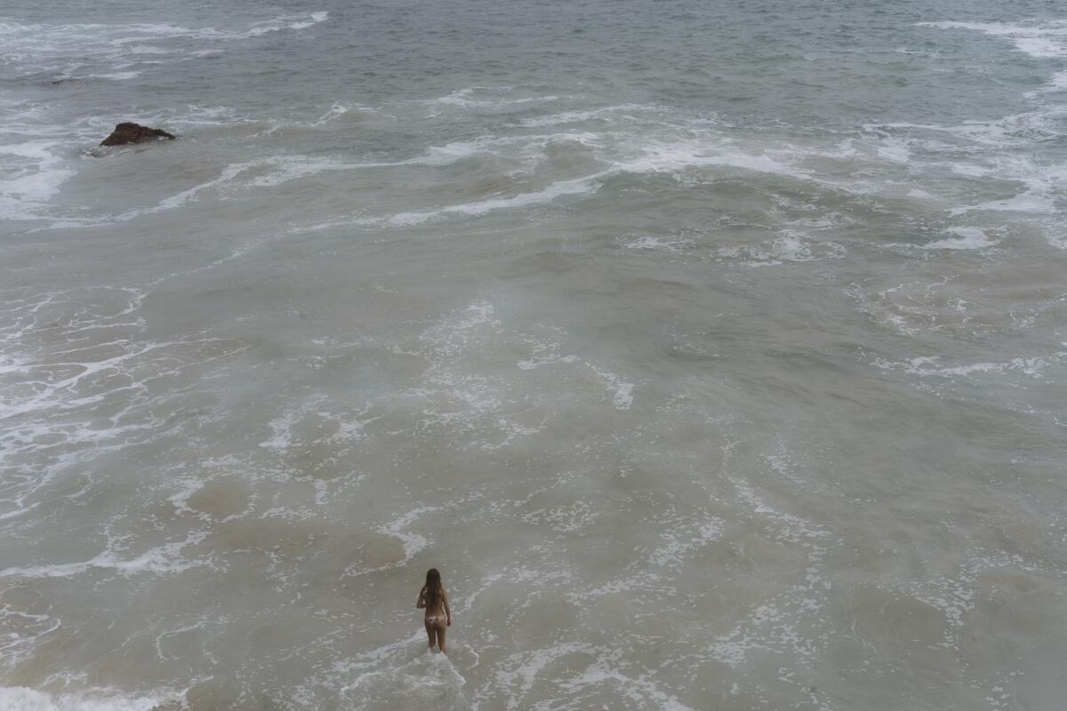 A woman stands in the ocean.