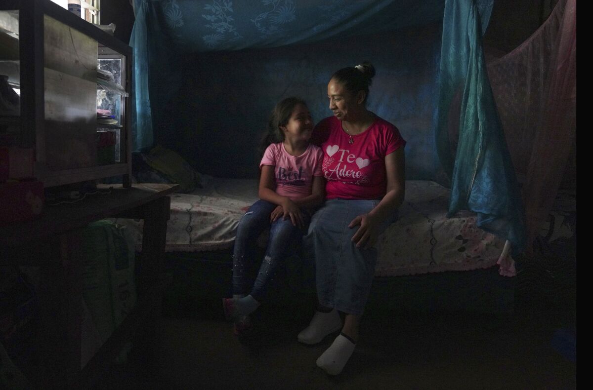 Mariana López sits with her seven-year-old daughter at their home in Ahuachapan, El Salvador, on Thursday, May 19, 2022. In 2000, López says she had an obstetric emergency, but was arrested on suspicion of inducing an abortion. She served 17 years in prison before being released when her 25-year sentence was commuted. (AP Photo/Jessie Wardarski)