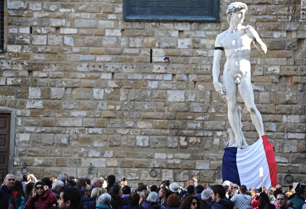 Una copia del David de Miguel Ángel está adornada con una bandera francesa y un listón negro en su brazo derecho en memoria de las personas fallecidas en los atentados en París, en Florencia, Italia.