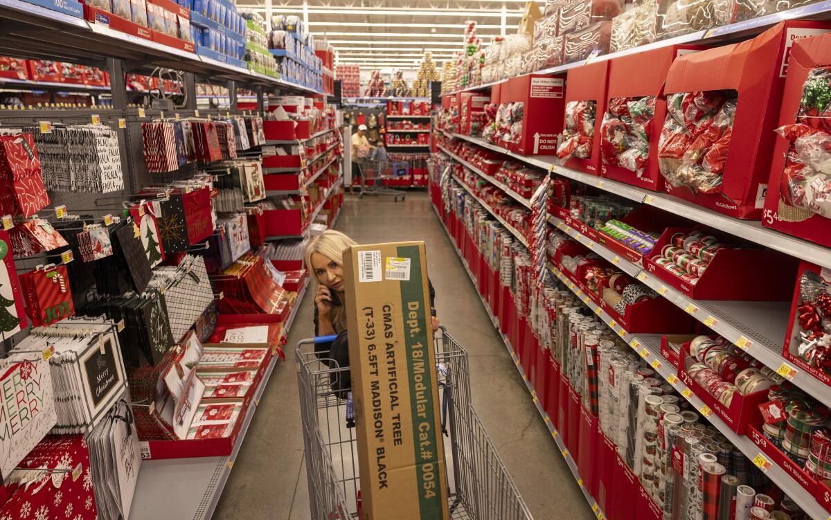 A customers rolls her cart past shelves stocked with holiday items 