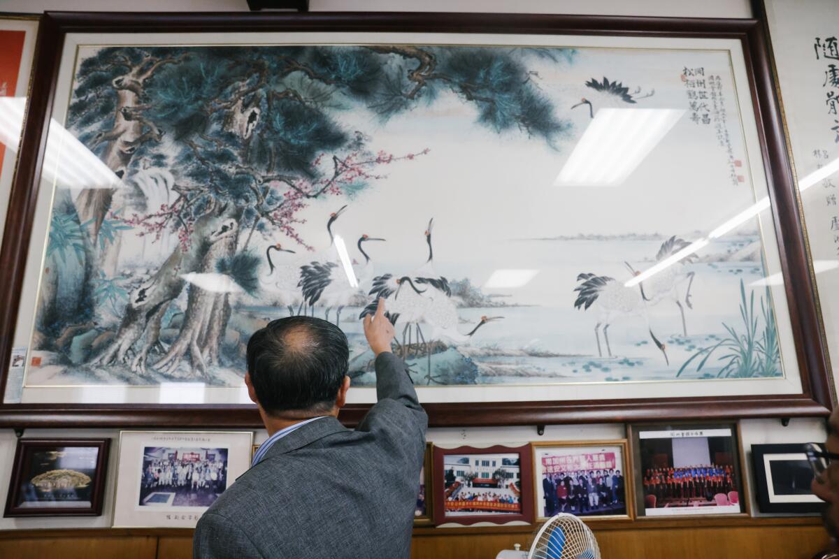 President and board director Thomas T. Lo points to an art piece created by the brother of one of China's emperors.