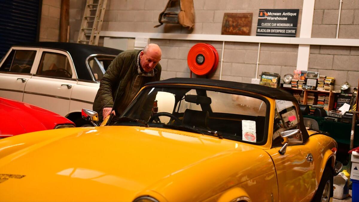 Hughie Nolan inspects a 1970s vintage Jaguar sports car for sale at his antique shop in Blacklion, Ireland, a town on the border with Northern Ireland.