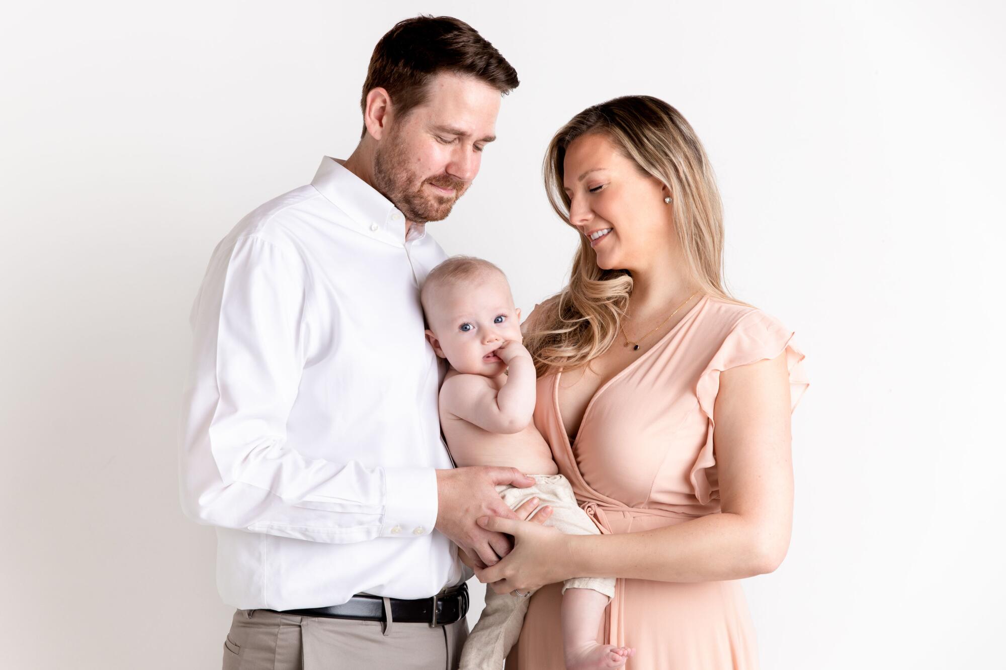 A man and a woman holding a baby.
