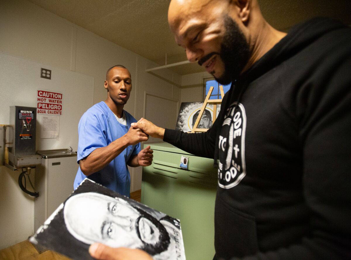 Common admires a portrait of himself painted by Yusef Pierce, 32, at the California Rehabilitation Center.