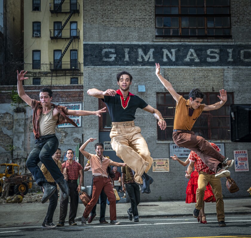 Three young men leap balletically on a New York street as other men watch. 