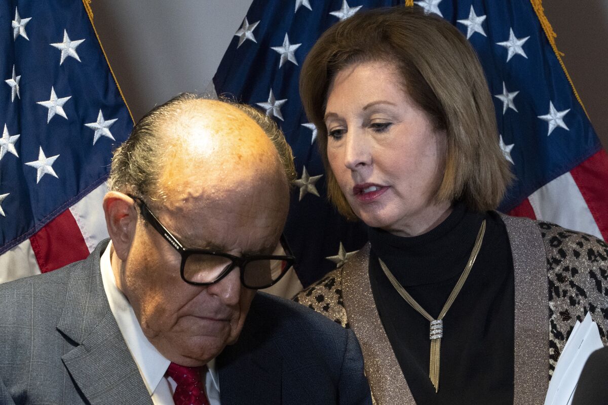 Rudolph Giuliani bows his head as he listens to Sidney Powell 